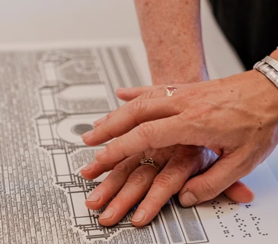 Mani che leggono una mappa tattile con scrittura Braille